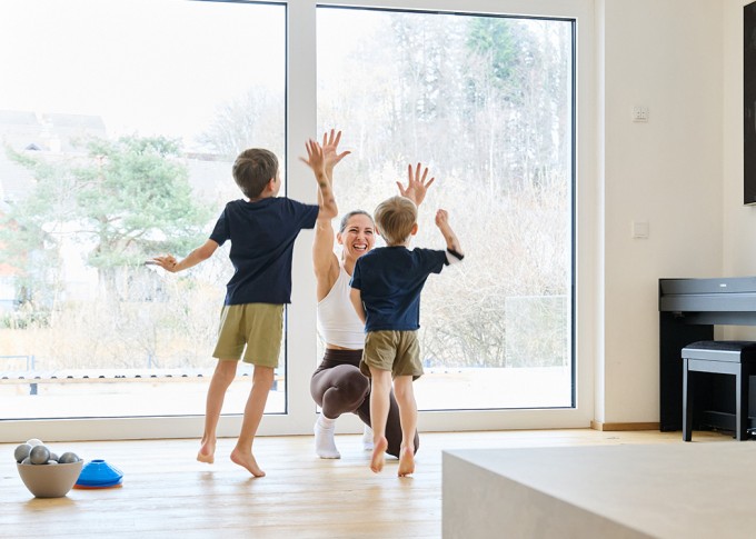 Frau macht Workout mit 2 Kindern und lächelt