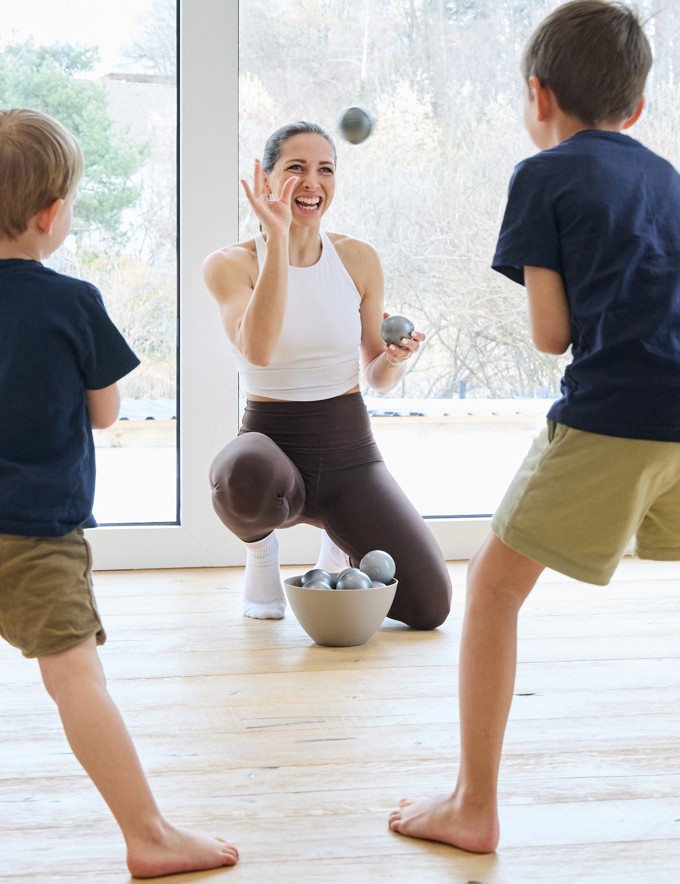 Frau macht Workout mit 2 Kindern und lächelt