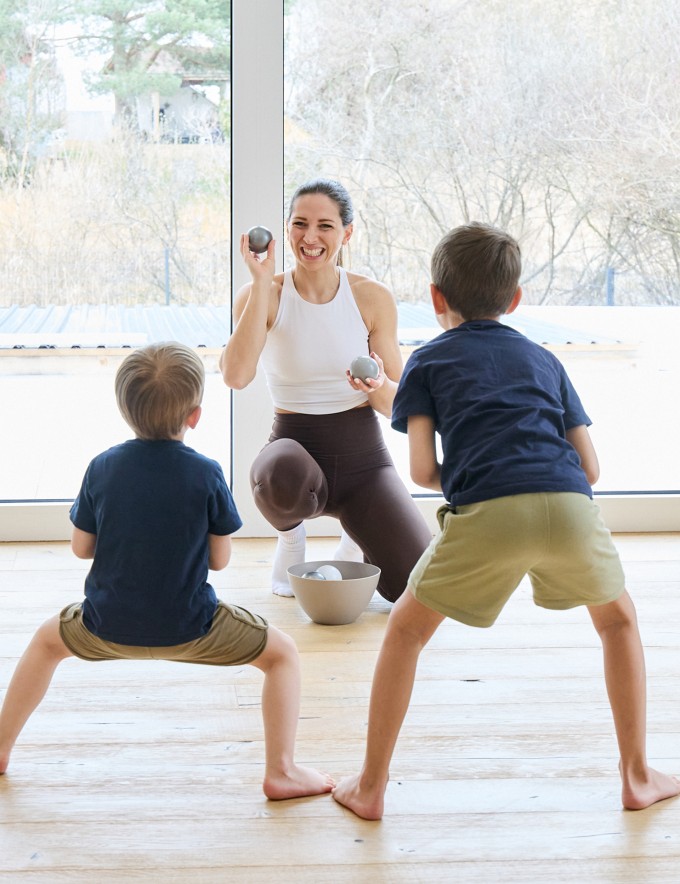 Frau macht Workout mit 2 Kindern und lächelt