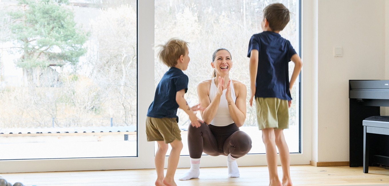 Frau macht Workout mit 2 Kindern und lächelt