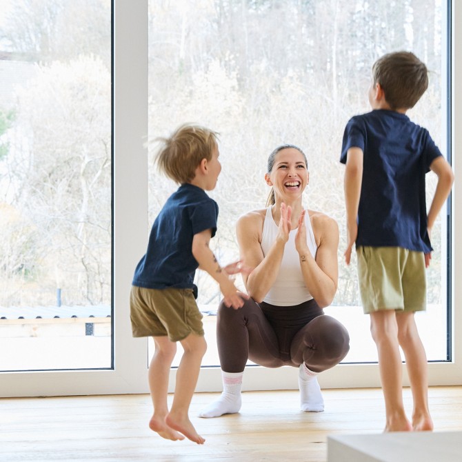 Frau macht Workout mit 2 Kindern und lächelt