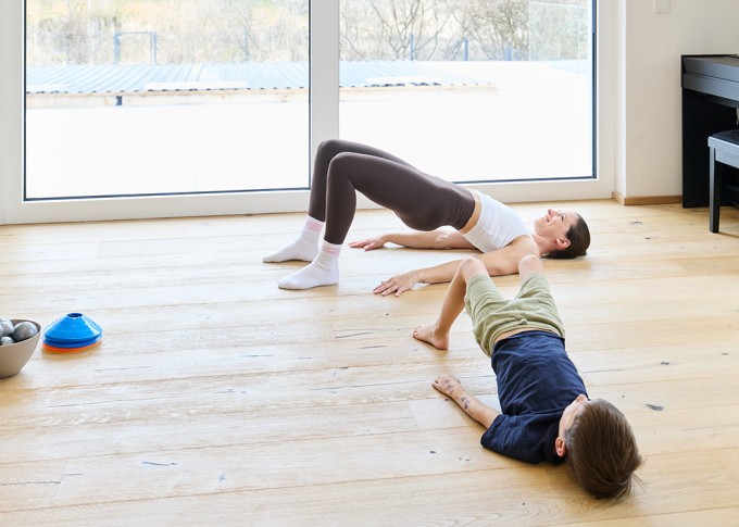 Frau macht Workout mit 2 Kindern und lächelt