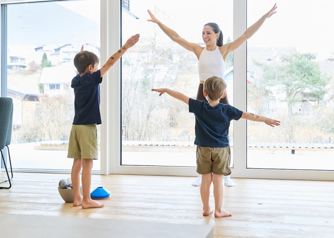 Frau macht Workout mit 2 Kindern und lächelt