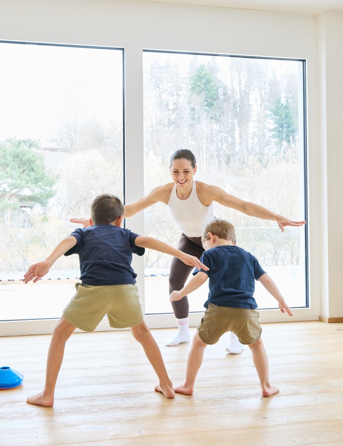 Frau macht Workout mit 2 Kindern und lächelt