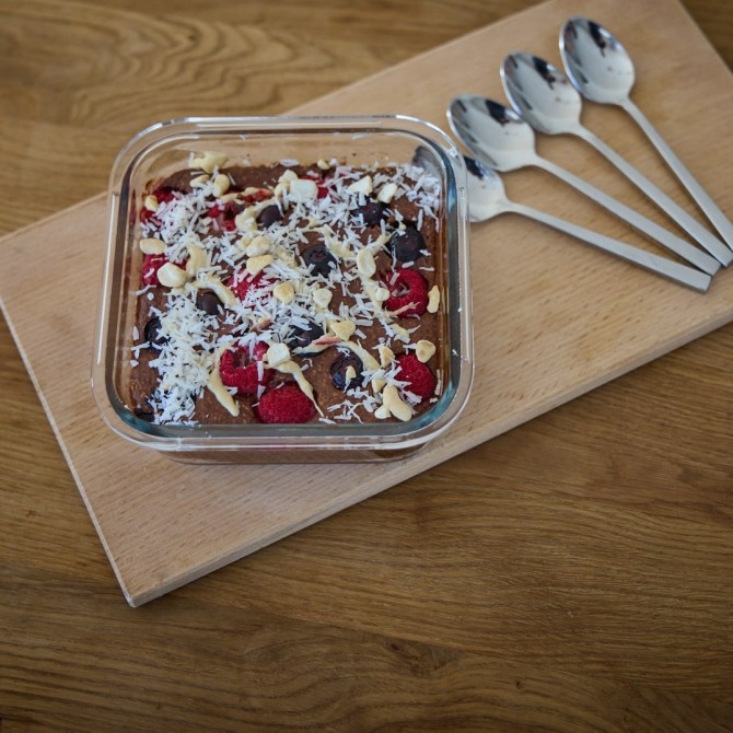 Schoko Hafertraum mit Beeren auf einer Holzplatte, daneben 4 Löffel