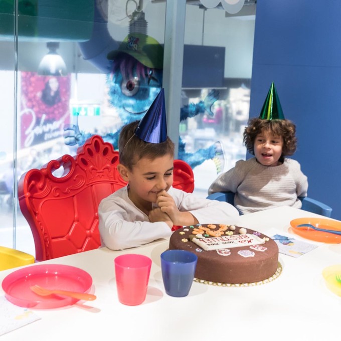 2 Kinder mit Hütchen vor der Geburtstagstorte im Lollipop