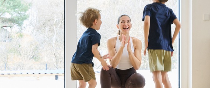 Frau macht Workout mit 2 Kindern und lächelt