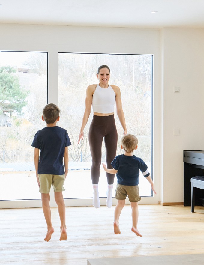 Frau macht Workout mit 2 Kindern und lächelt