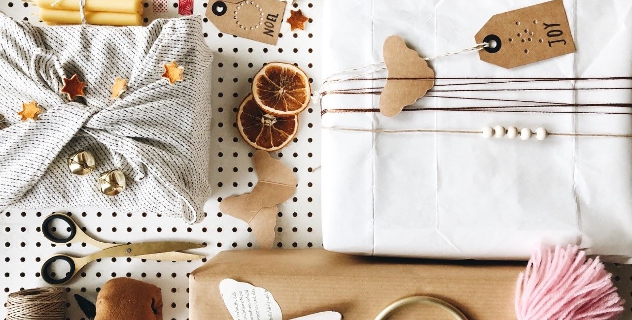 Drei Geschenke, daneben Schnur, Schere, Namenskarten und Deko. Alles im Weihnachtsdesign.