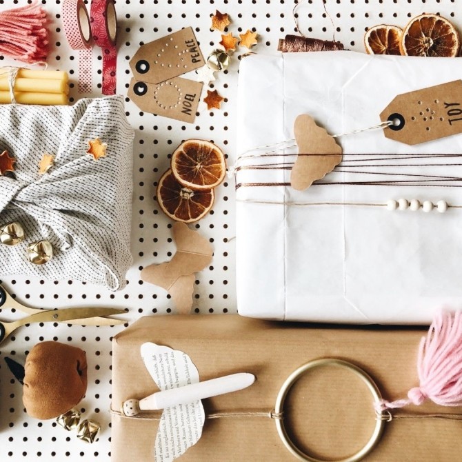 Drei Geschenke, daneben Schnur, Schere, Namenskarten und Deko. Alles im Weihnachtsdesign.