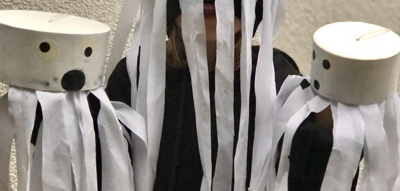 Kind mit zwei weißen Monstern in der Hand und ein weißes Monster am Kopf.