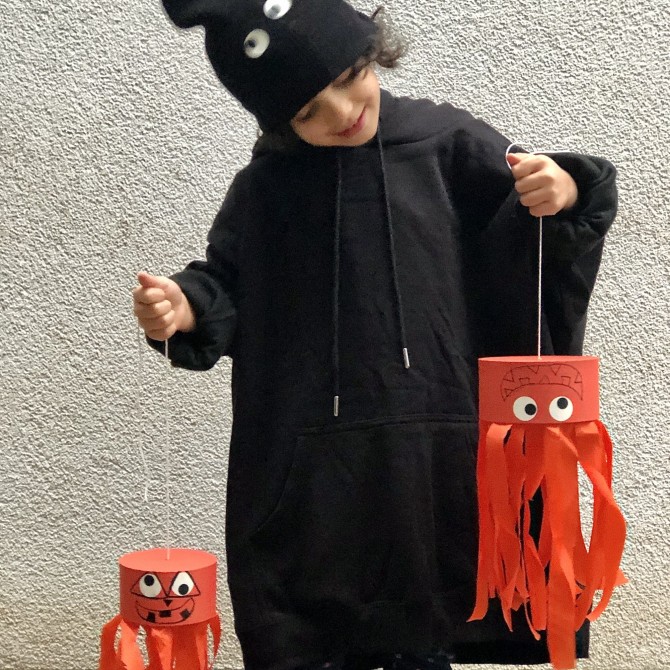 Kleiner Junge, der 2 orangefarbene Monster in der Hand hält.