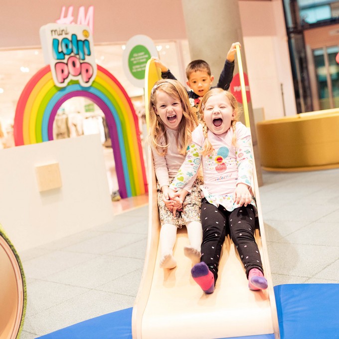 Drei Kinder sind im PLANET LOLLIPOP und rutschen eine kleine Rutsche herunter.